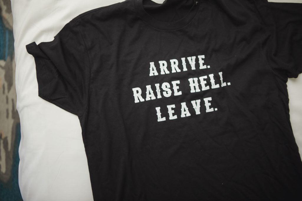 A black t-shirt with details that says arrive raise hell leave.
