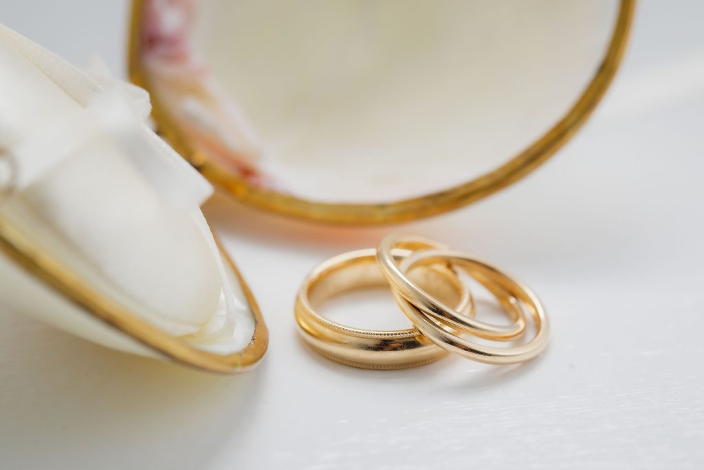 Two intricate wedding rings delicately placed on a elegant shell.