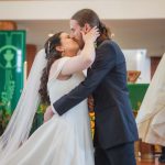 A wedding ceremony featuring a bride and groom sharing a kiss in front of a priest.
