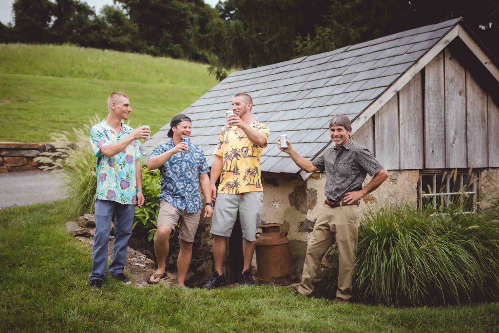 Four men in hawaiian shirts posing for a portrait.