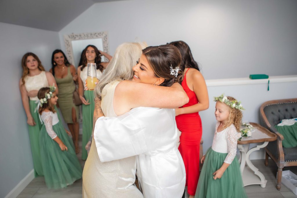 A candid wedding moment of a bride hugging her bridesmaids during preparations.