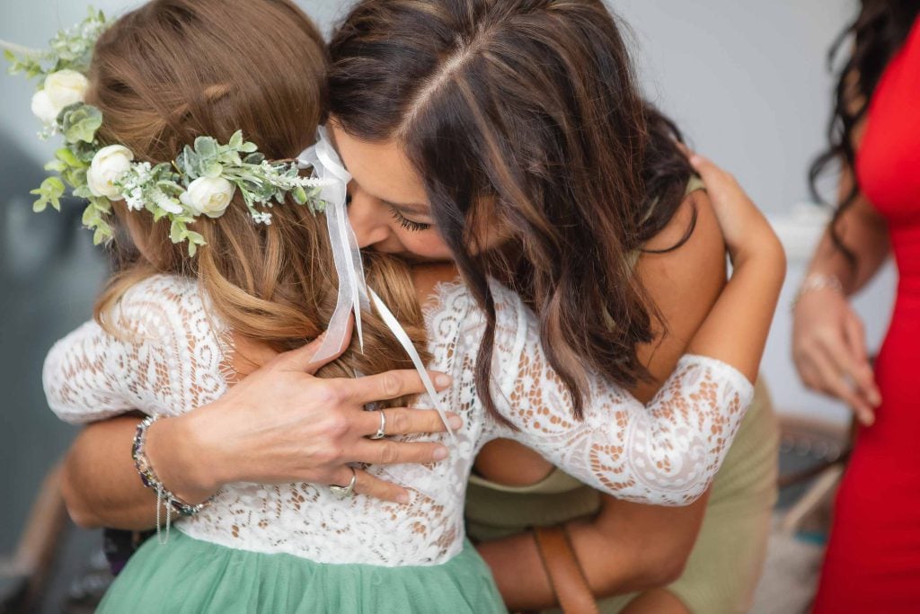 A candid moment at a wedding, as a woman lovingly hugs a little girl.