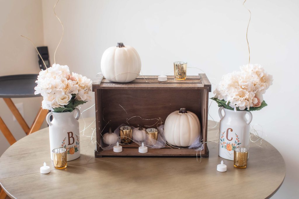 A rustic wedding centerpiece with pumpkins and flowers.