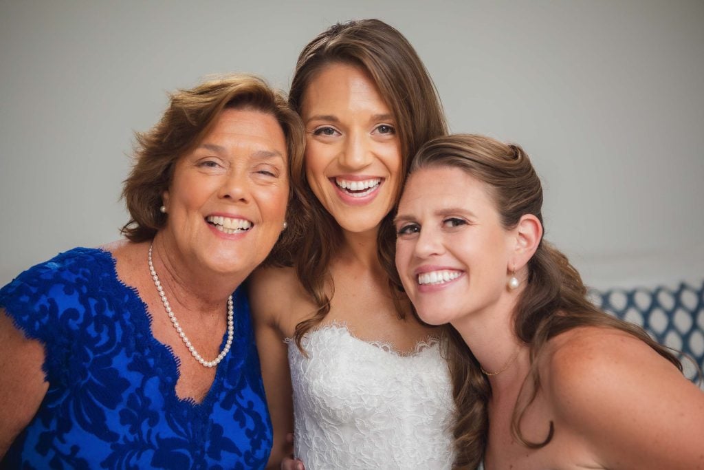 Three bridesmaids candidly posing for a photo during wedding preparation.