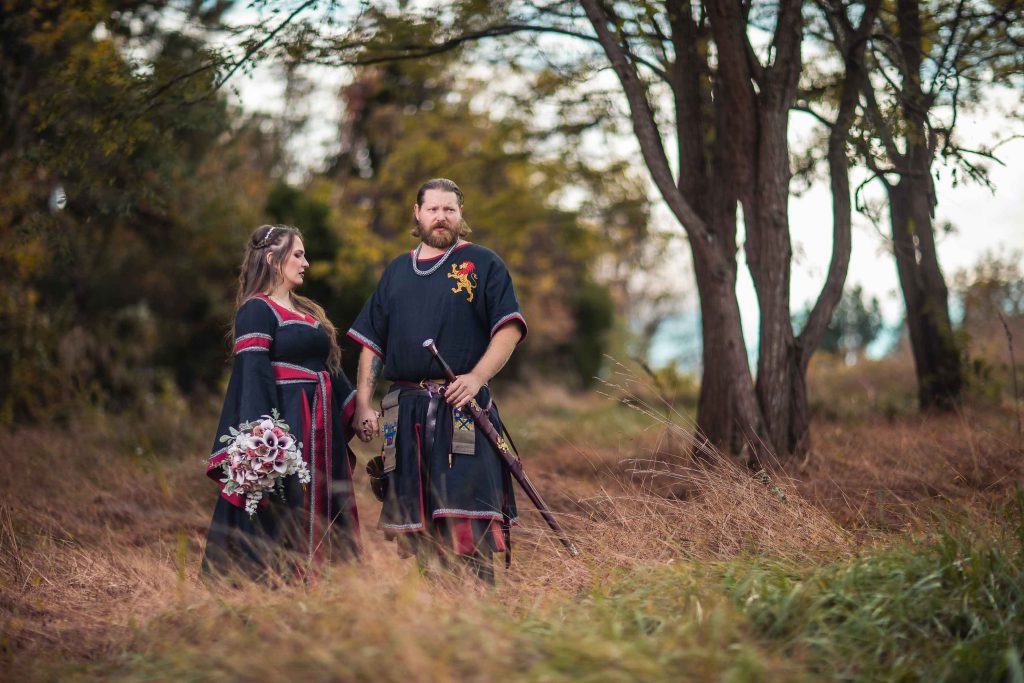 A medieval-themed wedding portrait in a field.