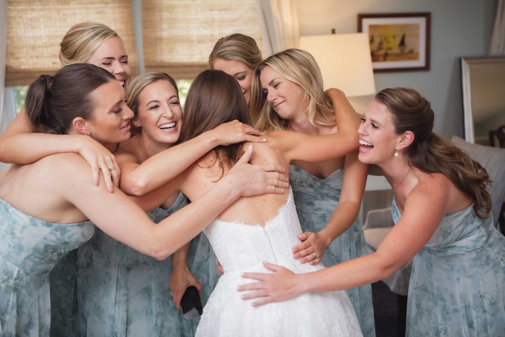 A candid moment of wedding preparation as a bride and her bridesmaids hug.