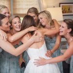 A candid moment of wedding preparation as a bride and her bridesmaids hug.