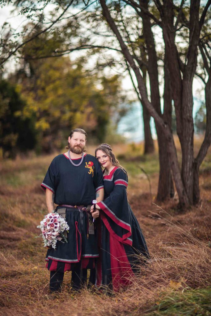 A medieval wedding portrait of a man and woman dressed in medieval costumes standing in a field.