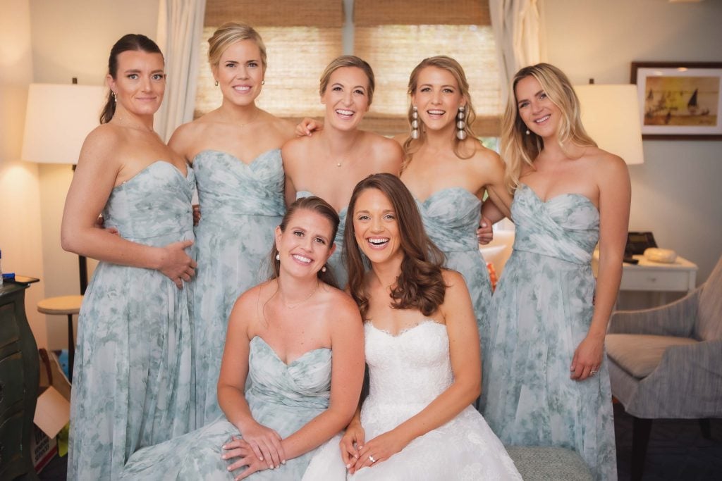 Bridesmaids candidly posing for a photo in a hotel room during wedding preparation.