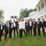 A group of groomsmen in tuxedos posing for a wedding portrait.