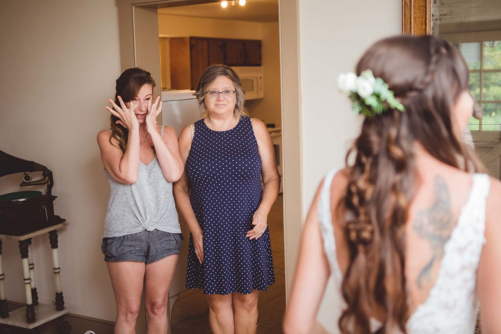 A candid moment captured during wedding preparation, as a bride and her mother gaze at each other in the mirror.