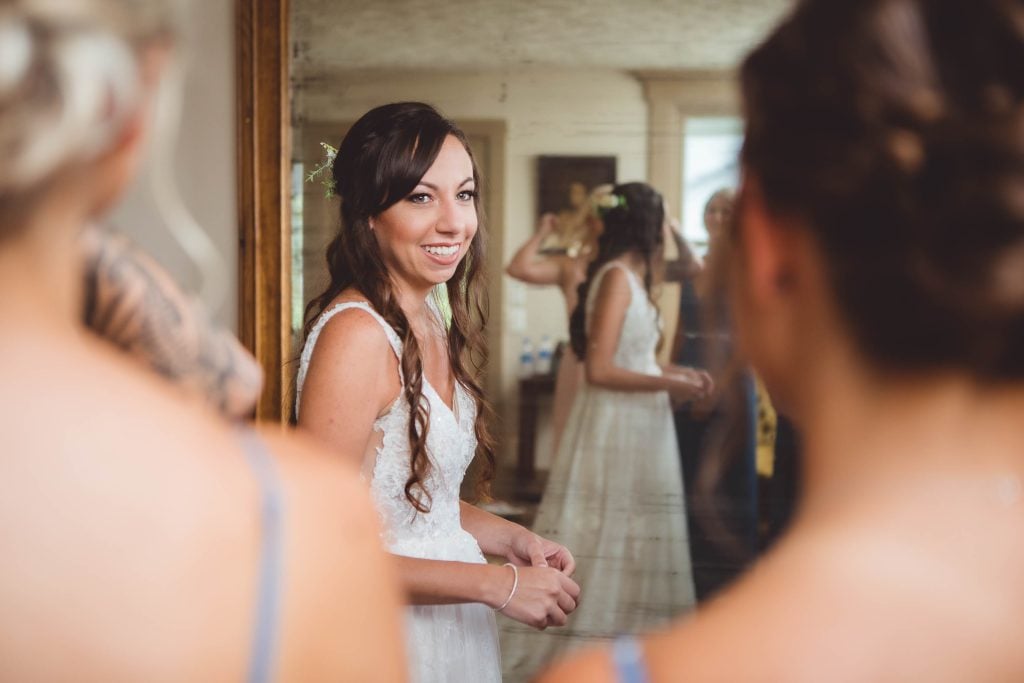 Candid preparation of a bride in front of a mirror.