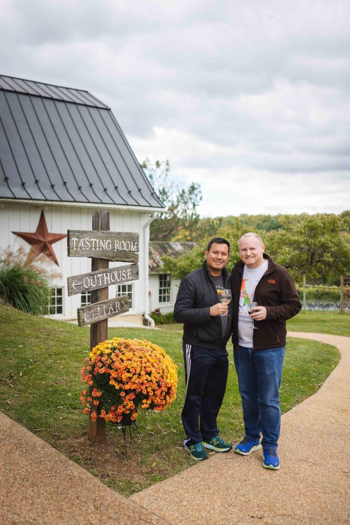 Two men candidly standing in front of a barn.