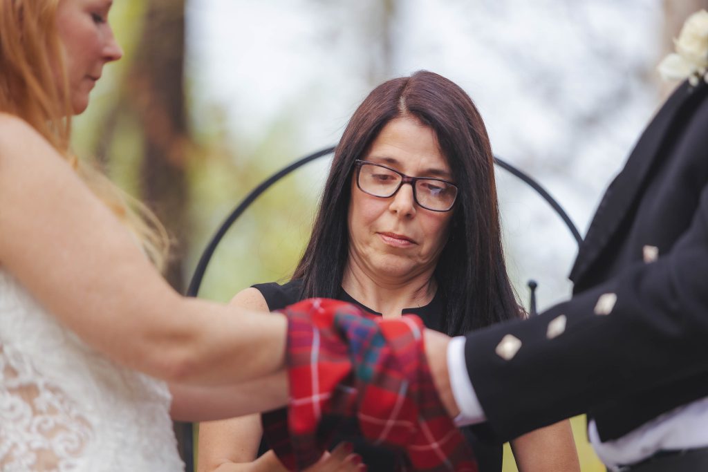 A man is putting a kilt on a woman's hand during a wedding ceremony.