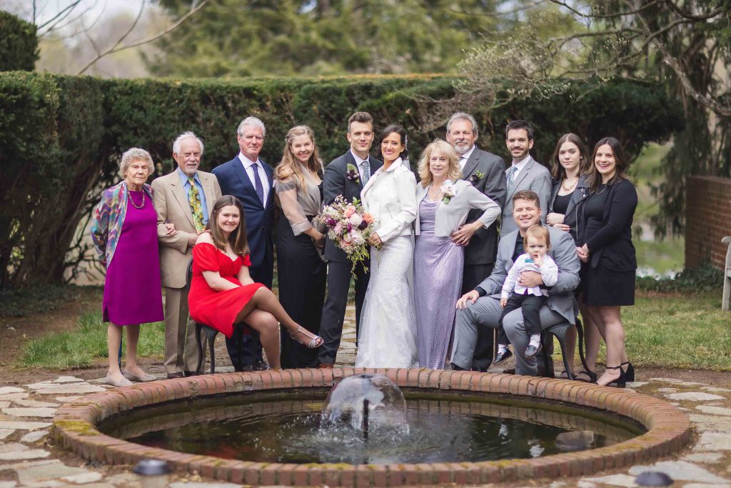 A group of people posing for a wedding portrait in front of a fountain.
