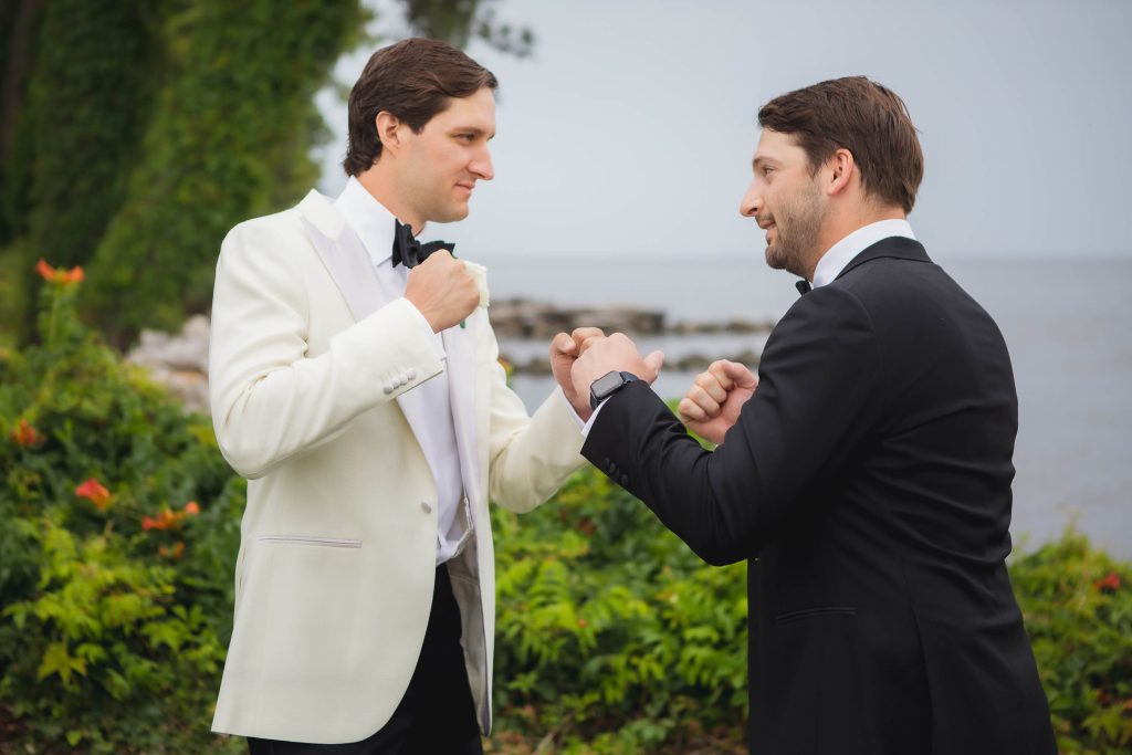 Two men in tuxedos standing next to each other at a wedding.