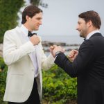 Two men in tuxedos standing next to each other at a wedding.