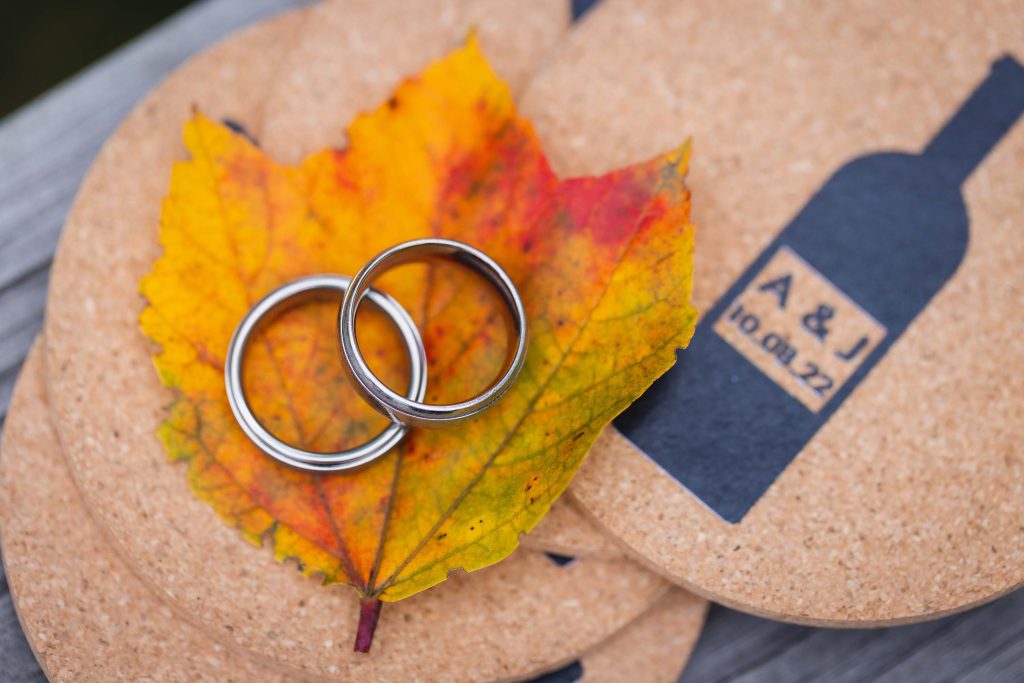 Wedding rings on a cork board adorned with fall leaf.