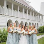 A wedding party poses in front of a house.
