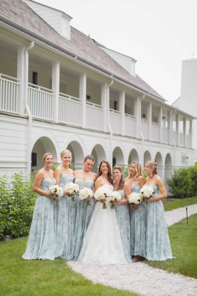 A wedding party poses in front of a house.