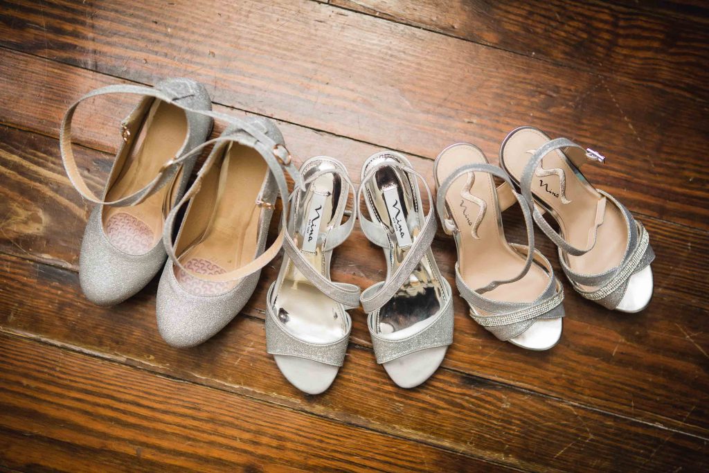 A row of wedding shoe details on a wooden floor.