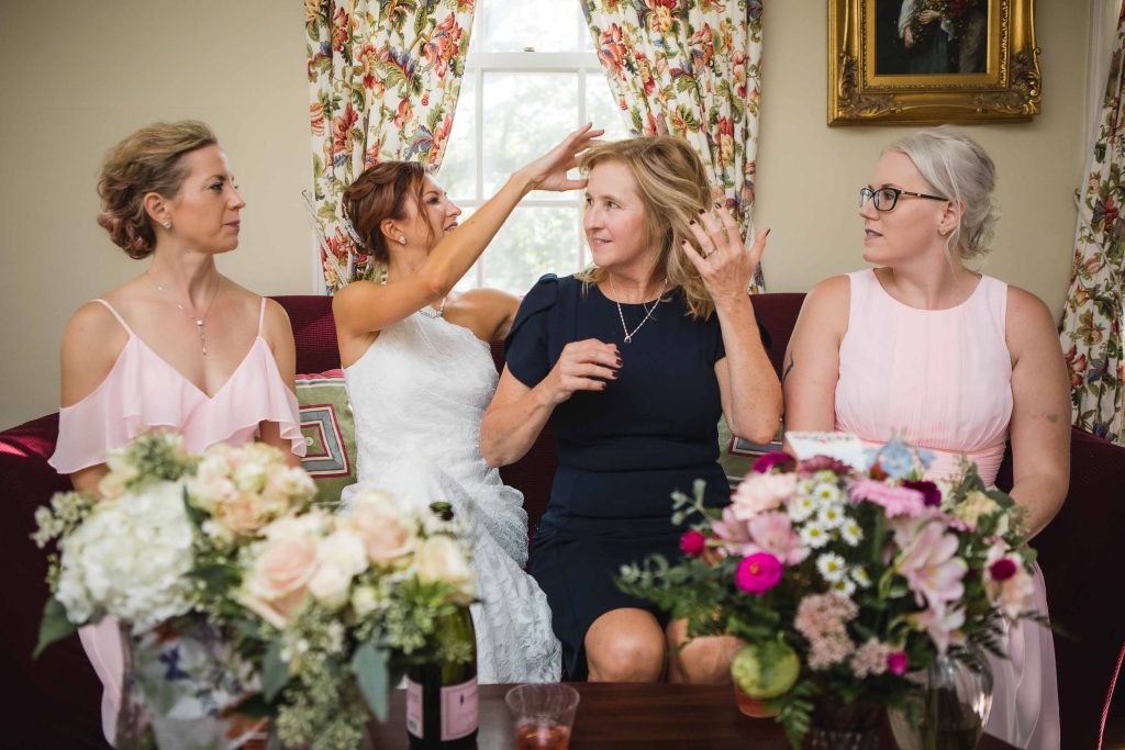 A candid group of bridesmaids preparing for a wedding, sitting on a couch.