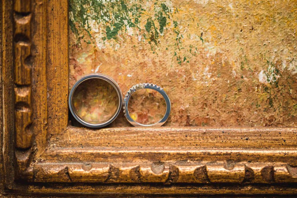Detailed close-up of two wedding rings displayed on a rustic wooden frame.