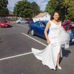 A candid bride in a white dress preparing for her wedding in a parking lot.