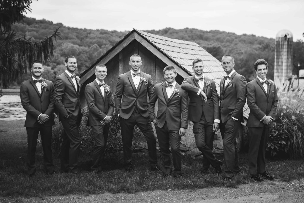 Groomsmen posing for a wedding portrait in front of a barn.