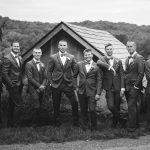 Groomsmen posing for a wedding portrait in front of a barn.