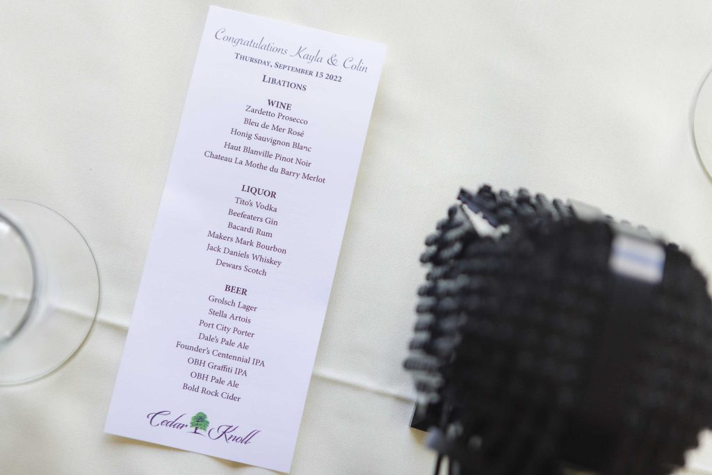 A wedding menu is beautifully displayed next to a glass of wine, highlighting the intricate details.