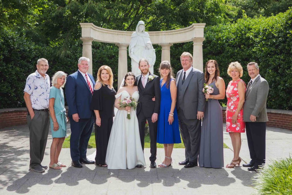 A wedding party posing in front of a statue for a portrait.