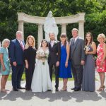 A wedding party posing in front of a statue for a portrait.