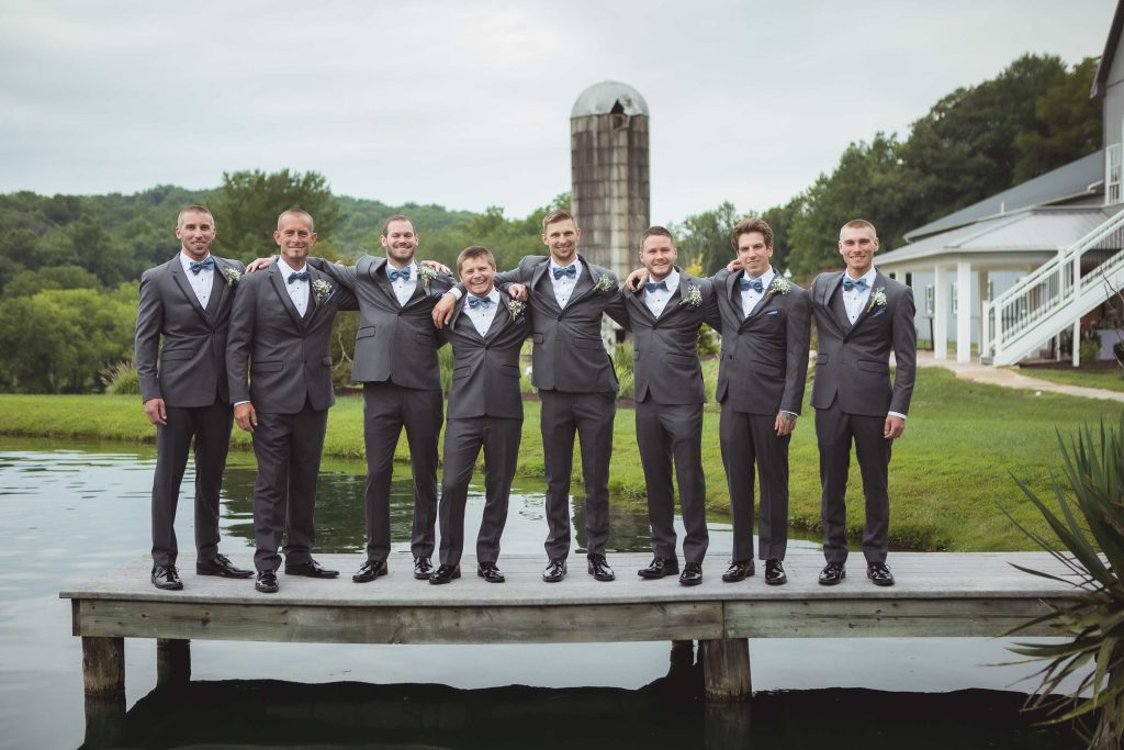 A portrait of groomsmen on a dock at a wedding.