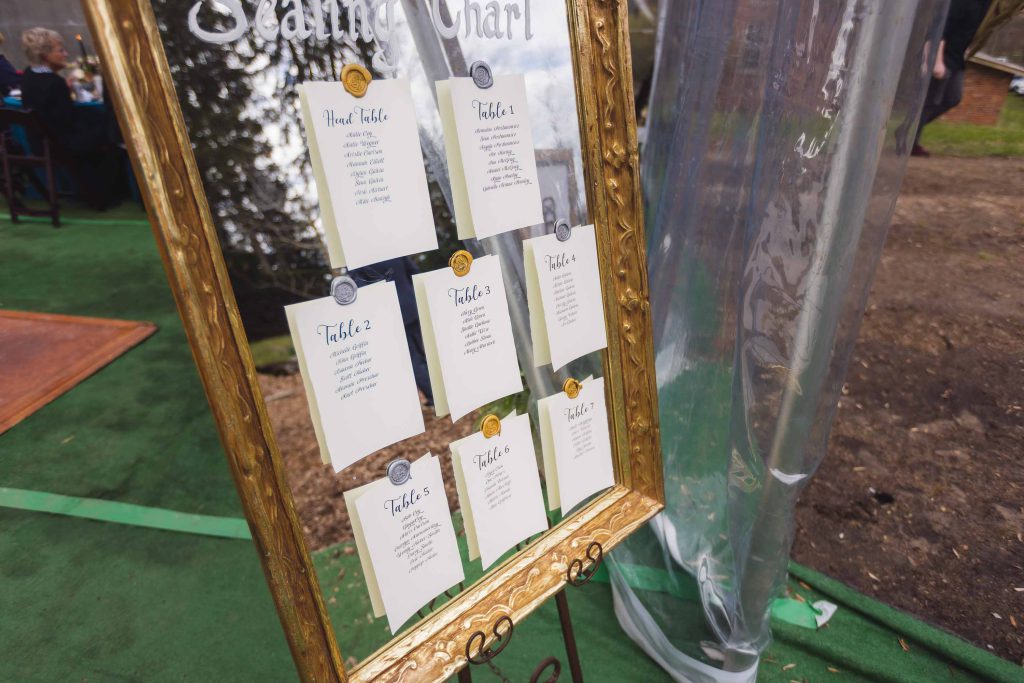 A mirror with a seating chart displaying wedding details.