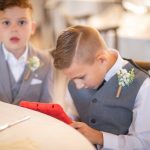Candid preparation at a wedding with two young boys using a tablet computer.