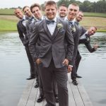 A group of groomsmen posing for a wedding portrait on a dock.