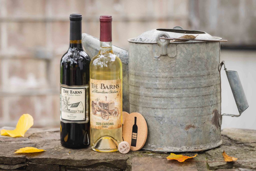 A wedding detail featuring two bottles of wine and a bucket on a stone wall.