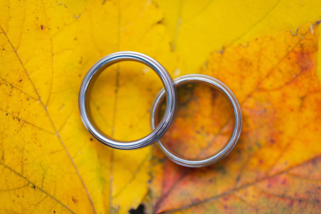 Two wedding rings on a yellow leaf background showcasing intricate details.