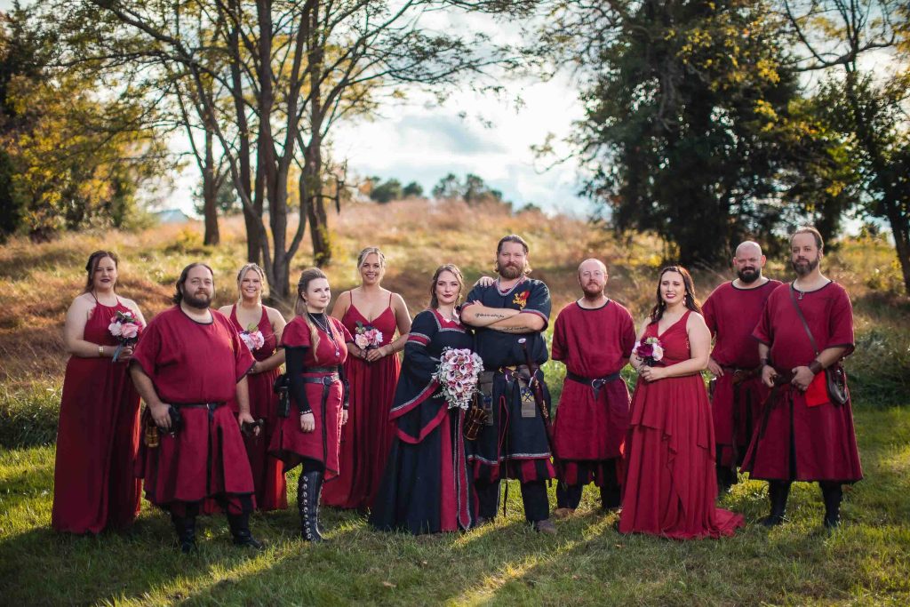 A wedding portrait of a party in red costumes posing for a picture.