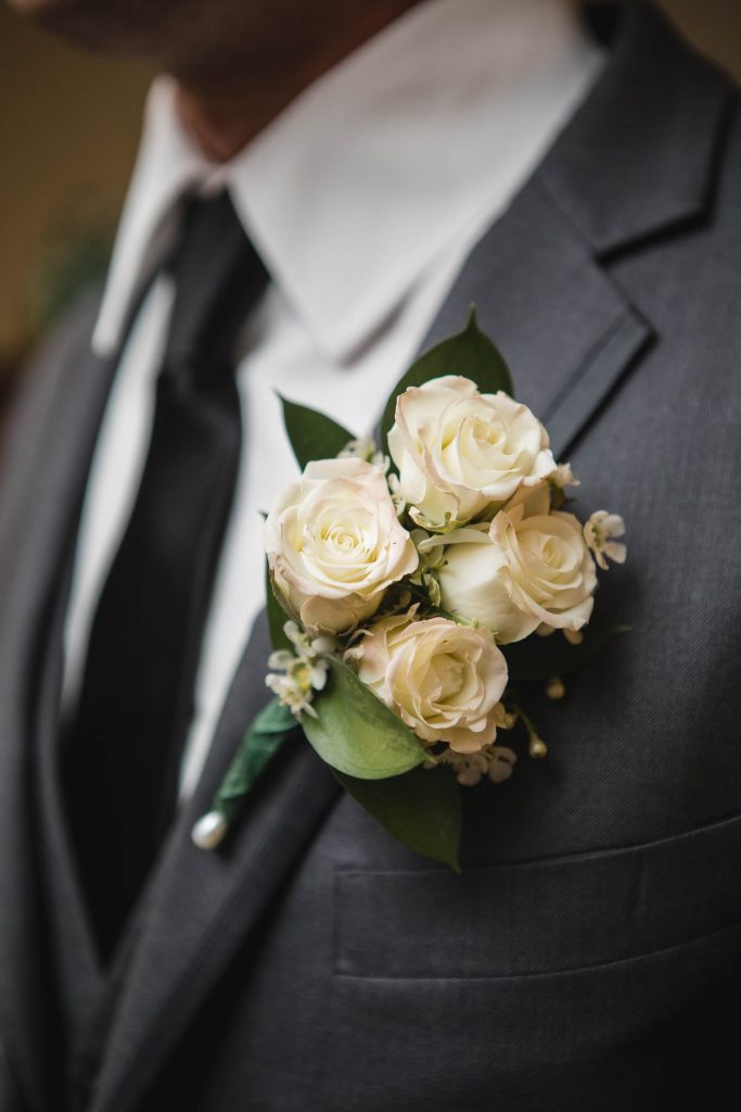 A wedding boutonniere featuring white roses, adding exquisite details to the groom's suit.