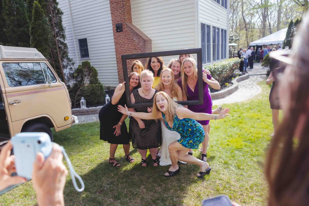 A group of bridesmaids posing for a photo at a wedding reception in front of a VW van.