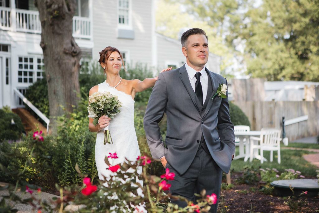 A candid bride and groom walking in front of a house.