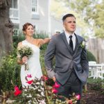 A candid bride and groom walking in front of a house.