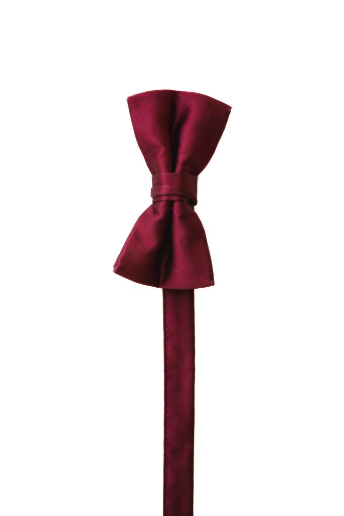 A burgundy bow tie with wedding details on a white background.
