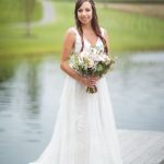 A wedding portrait of a bride holding her bouquet on a dock.