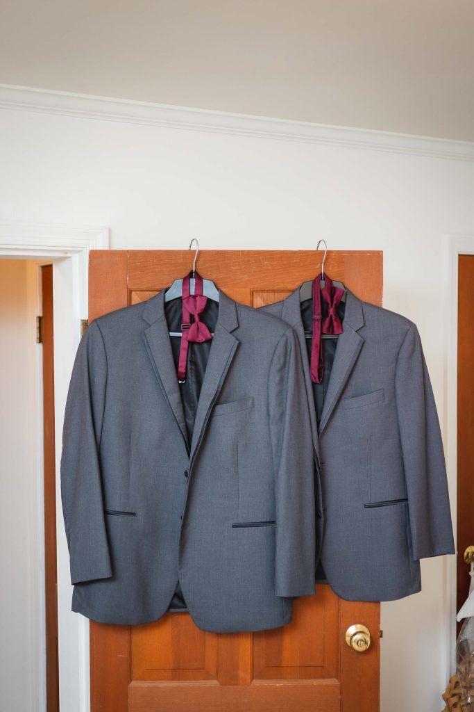 Two elegant wedding suits hanging on a door.