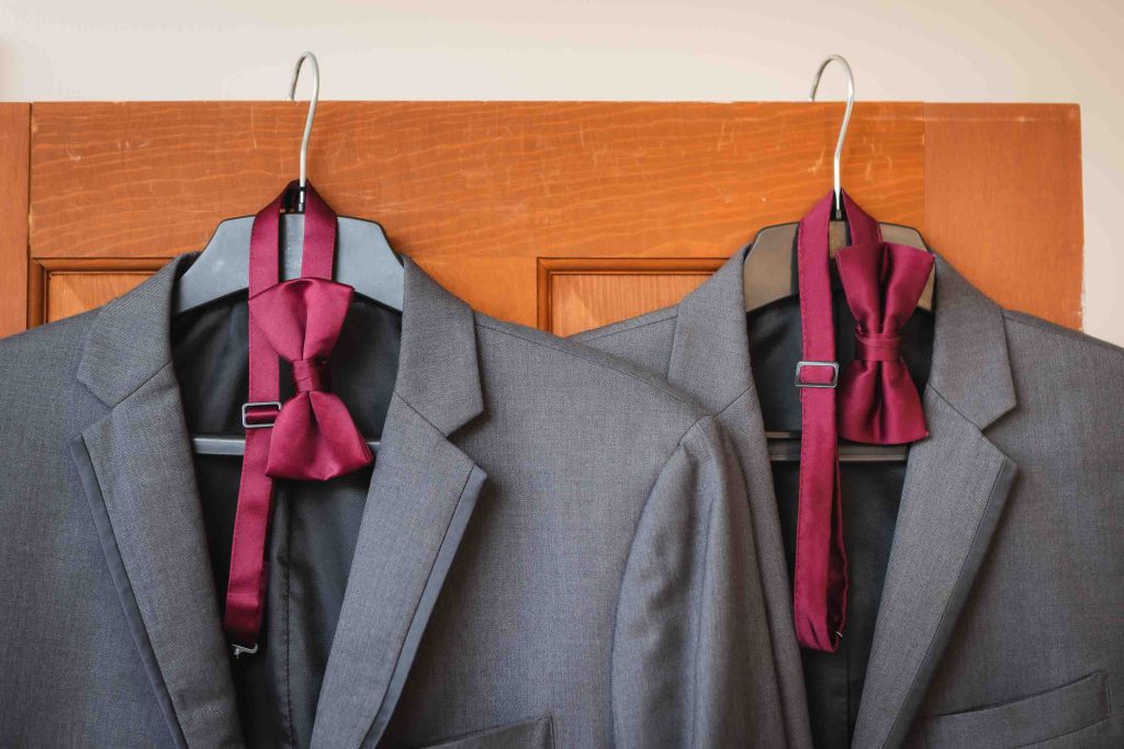Two suit jackets hanging on a door, showcasing wedding attire.