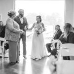 A black and white photo capturing the wedding ceremony as the bride and groom walk down the aisle.