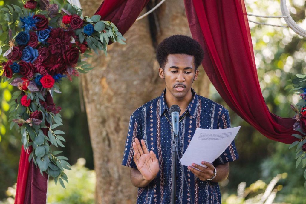 A man is reading a poem at a wedding ceremony.